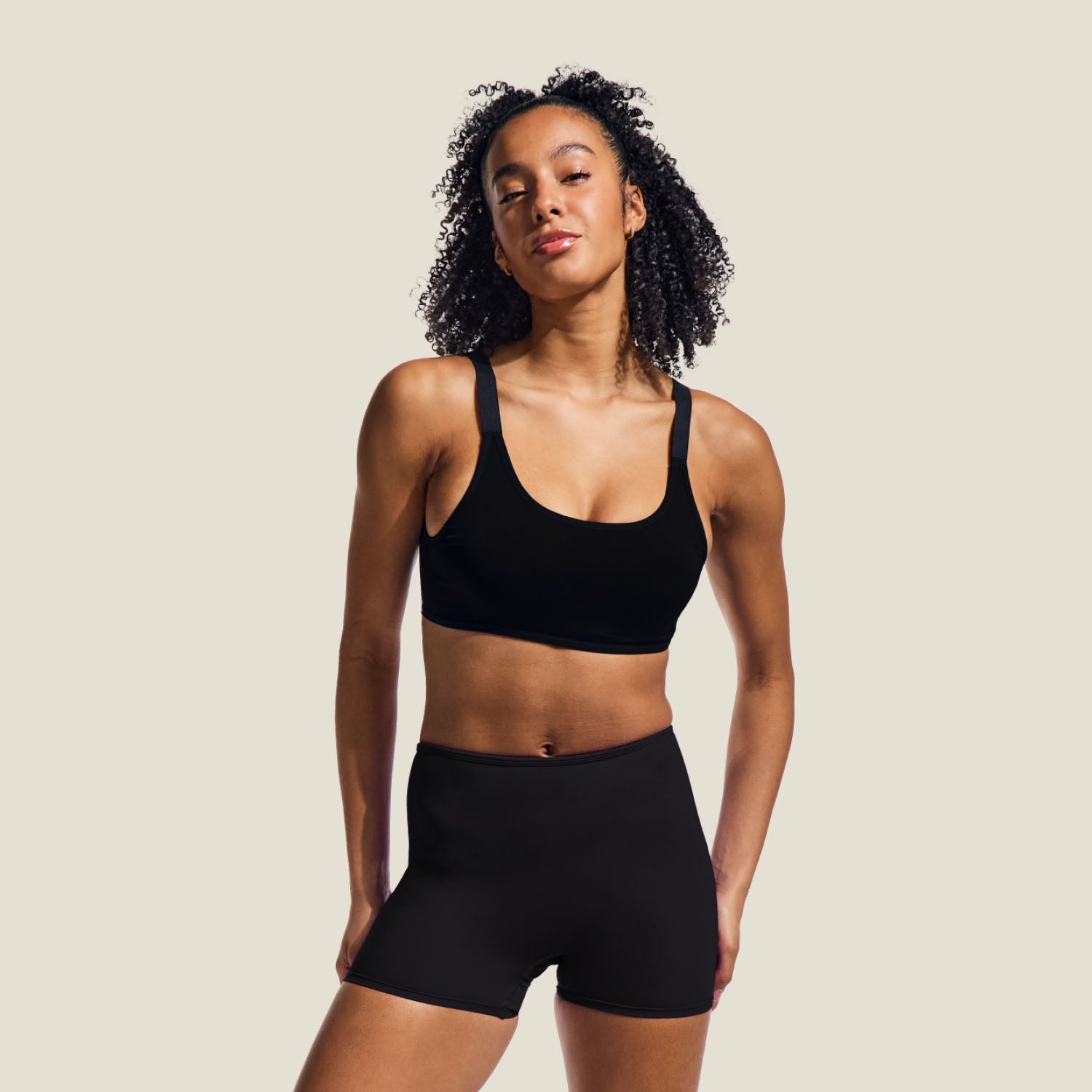 Teen model wears WUKA Teen Swim Shorts for medium flow, full-length view showing sleek black design with mid-thigh coverage and secure waistband.