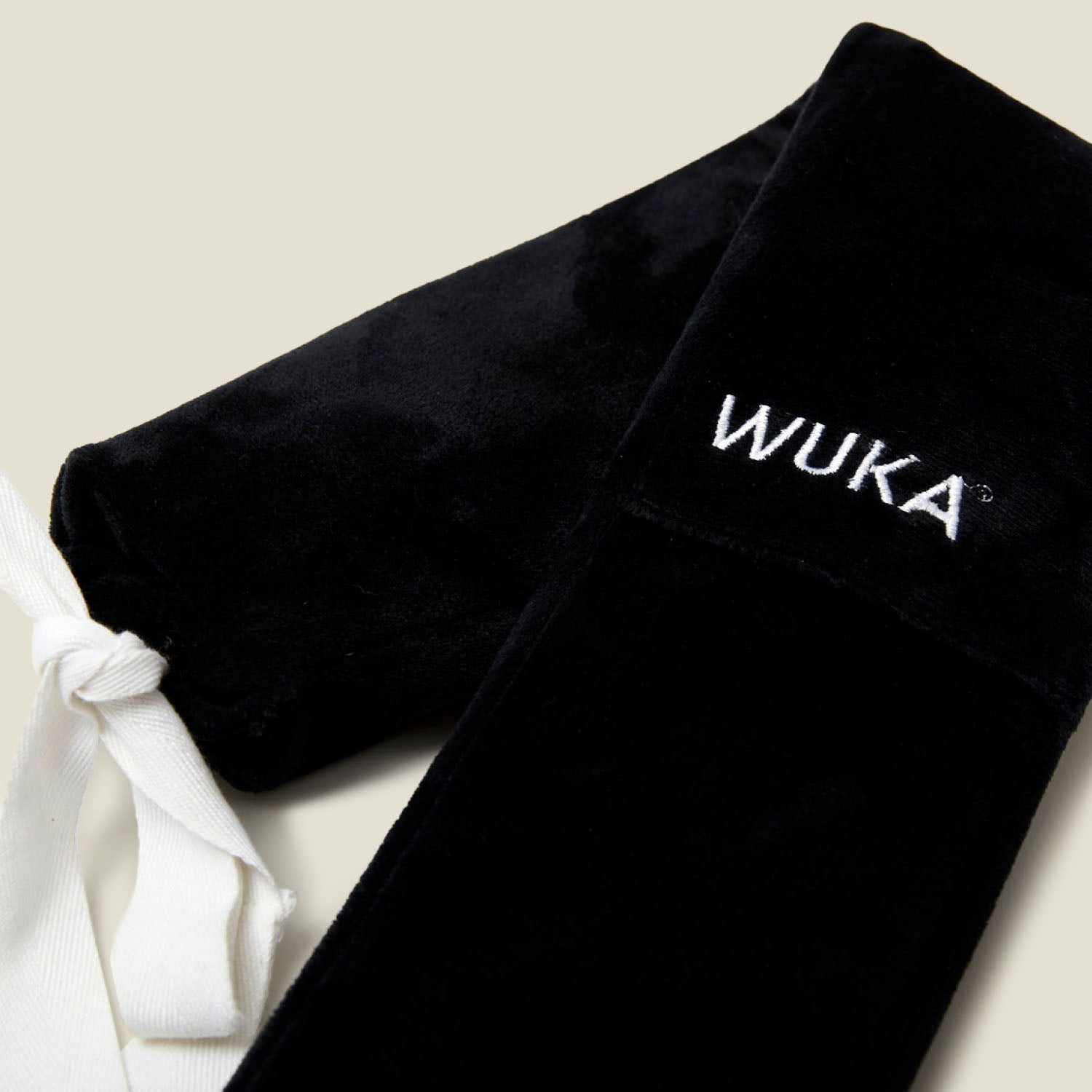 Close-up of WUKA branded wearable hot water bottle showing soft fleece material and detailed stitching.