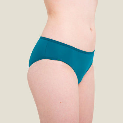 Side angle of teen model wearing WUKA blue swim period bikini brief for light flow, showing smooth edges and flattering cut.