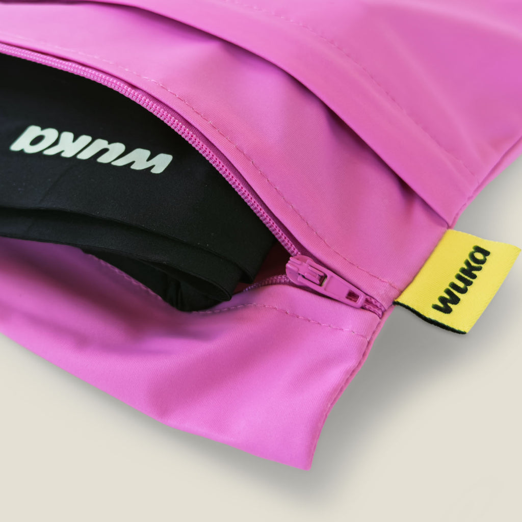 Close-up of the WUKA pink two-pocket changing bag showing quality zip closure and branded fabric tag